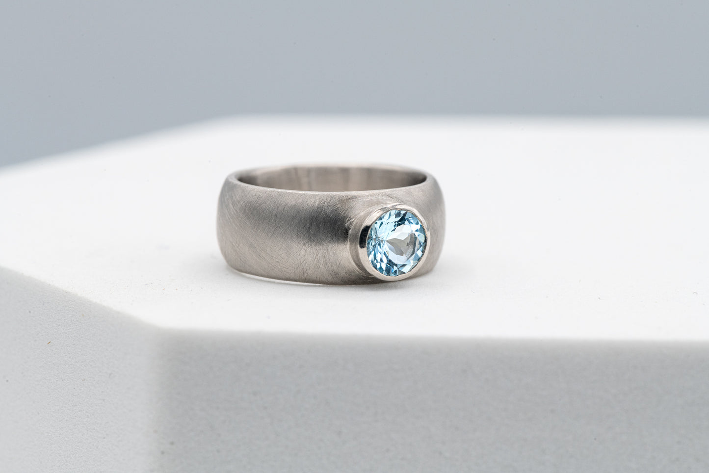 A handmade Chunky White Gold Engagement Ring with a blue topaz stone by Cassin Jewelry.