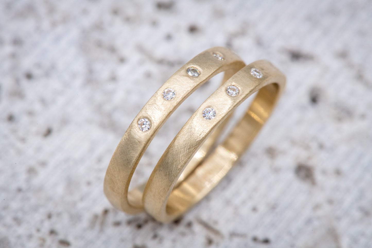 A pair of handmade gold wedding bands with Moissanite and diamonds.