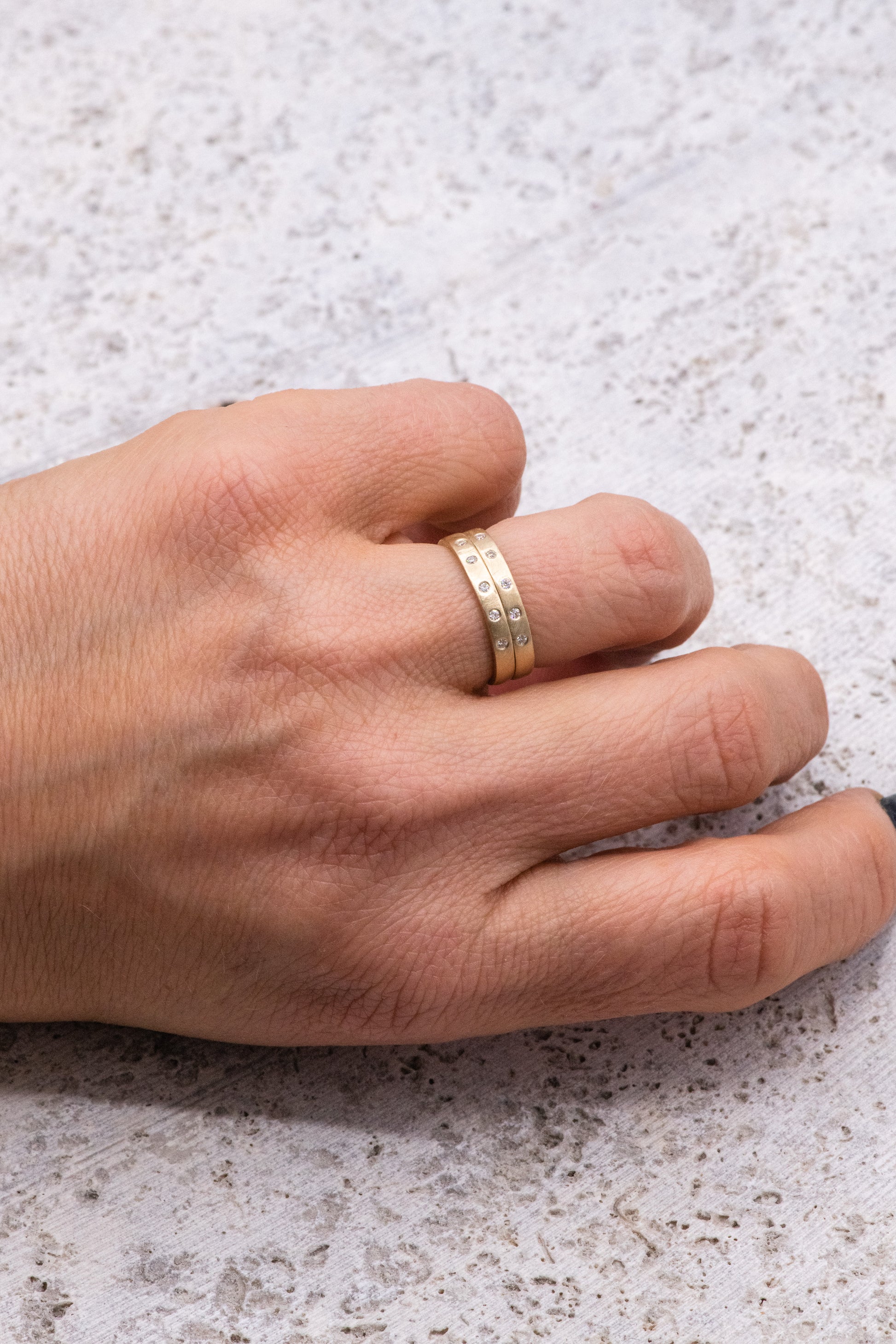 A woman's hand with a Moissanite Gold Wedding Band by Cassin Jewelry.