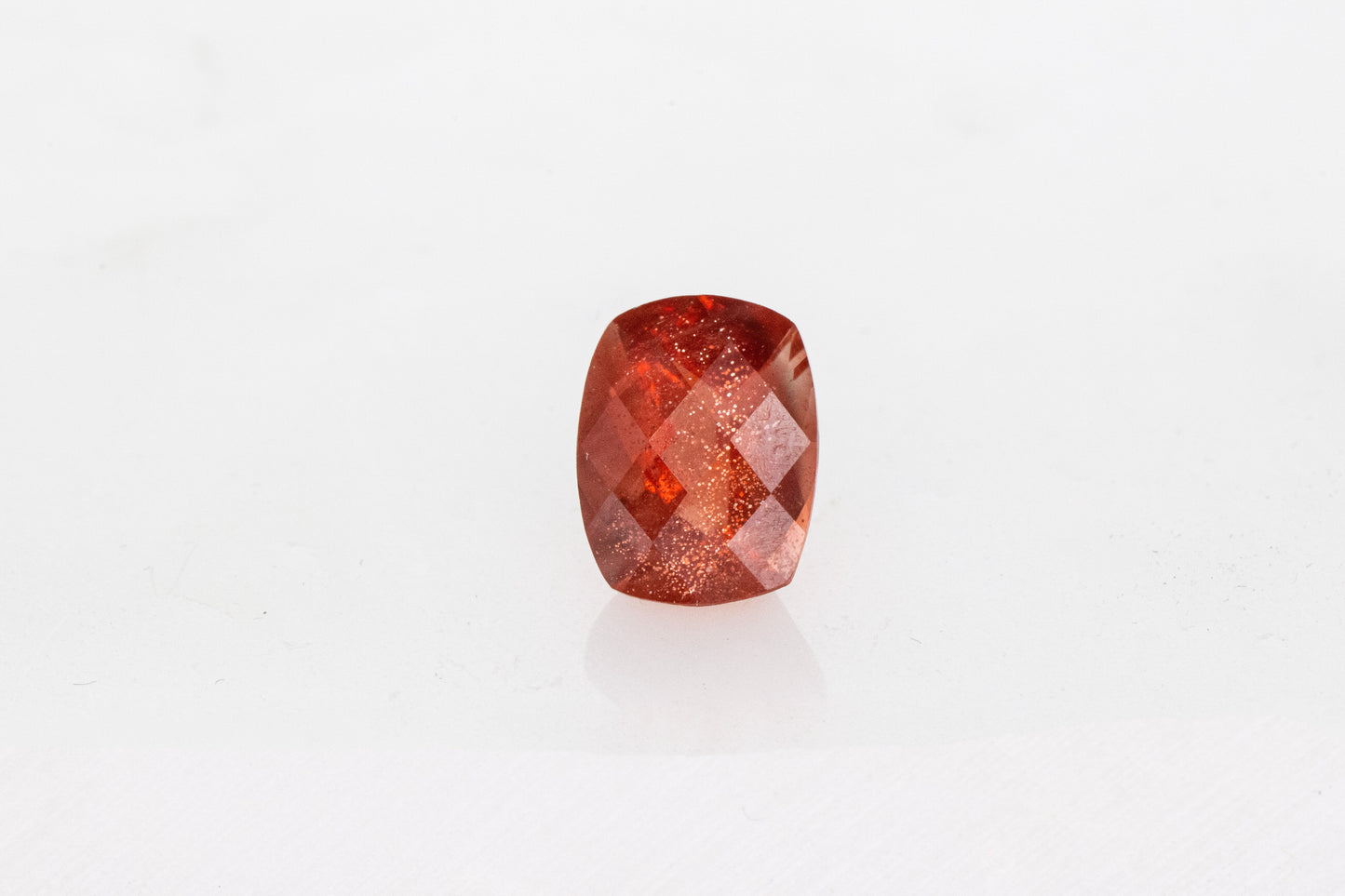 A Handmade Oregon Sunstone Cushion Cut 9x7mm on a white surface.