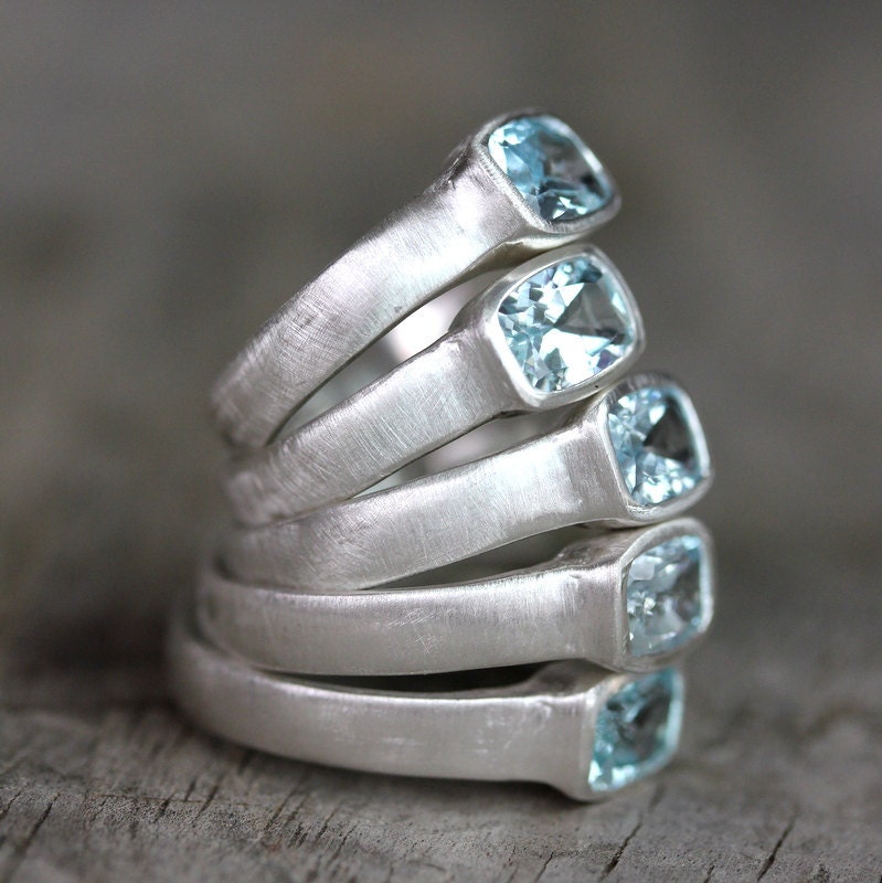 A stack of Low Bezel Set Handmade Aquamarine Sterling Silver Rings with blue topaz stones.