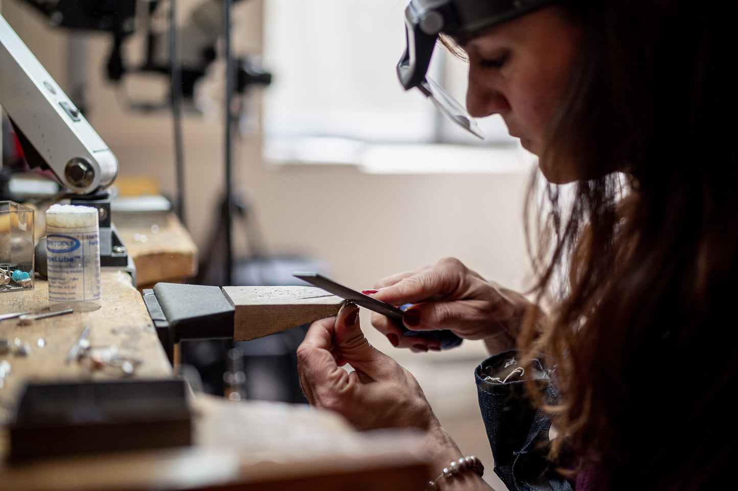 A woman is working on a handmade Round Oregon Sunstone Ring in Sterling Silver for Cassin Jewelry.