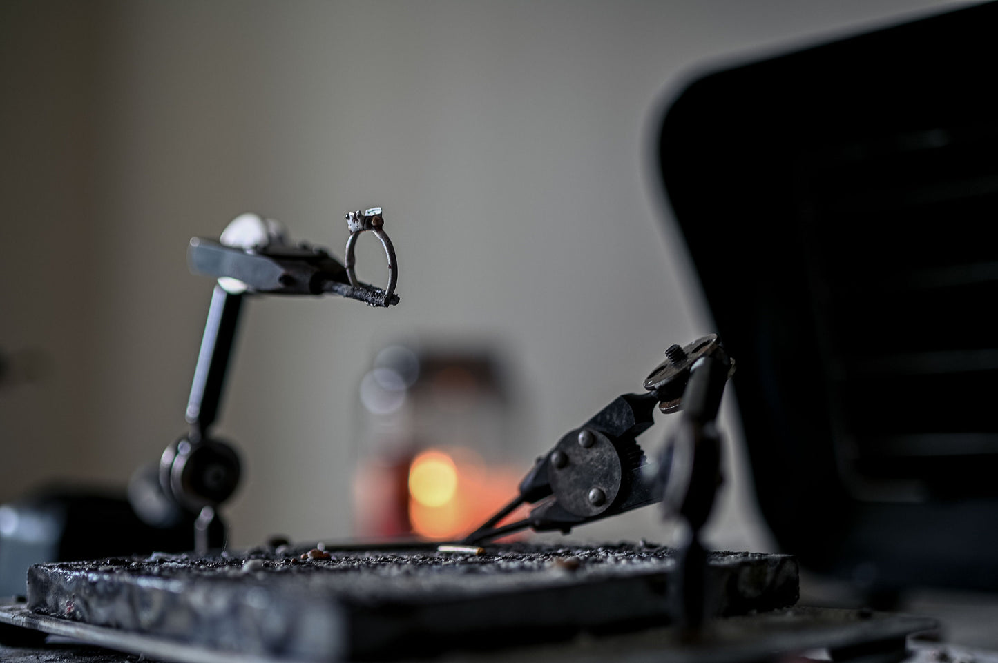 A handmade jewelry piece, a Low Bezel Set Aquamarine Cushion Cut Sterling Silver Ring, is displayed on a table next to a piece of metal.