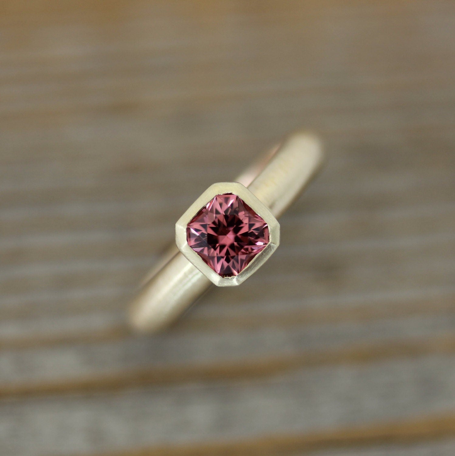 A handmade Asscher Cut Pink Spinel Ring in 14k Yellow Gold with a pink sapphire in the center.