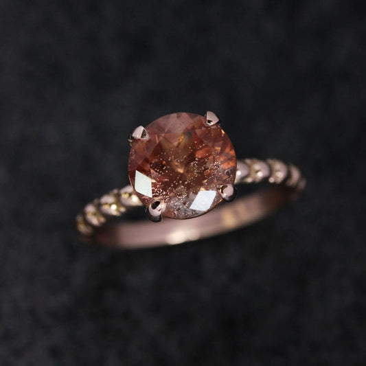 A Handmade Oregon Sunstone Ring in Rose Gold with a brown diamond by Cassin Jewelry.