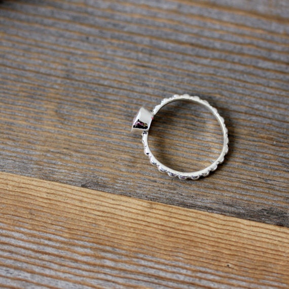 A Morganite, Peridot and Rhodolite Garnet Ring in Recycled Sterling Silver handmade jewelry on a wooden table.