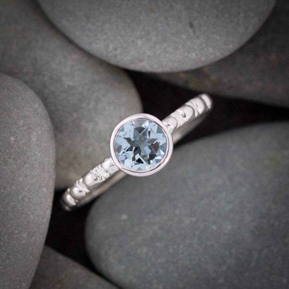 A handmade Round Aquamarine Ring Silver Ring with a blue topaz stone.