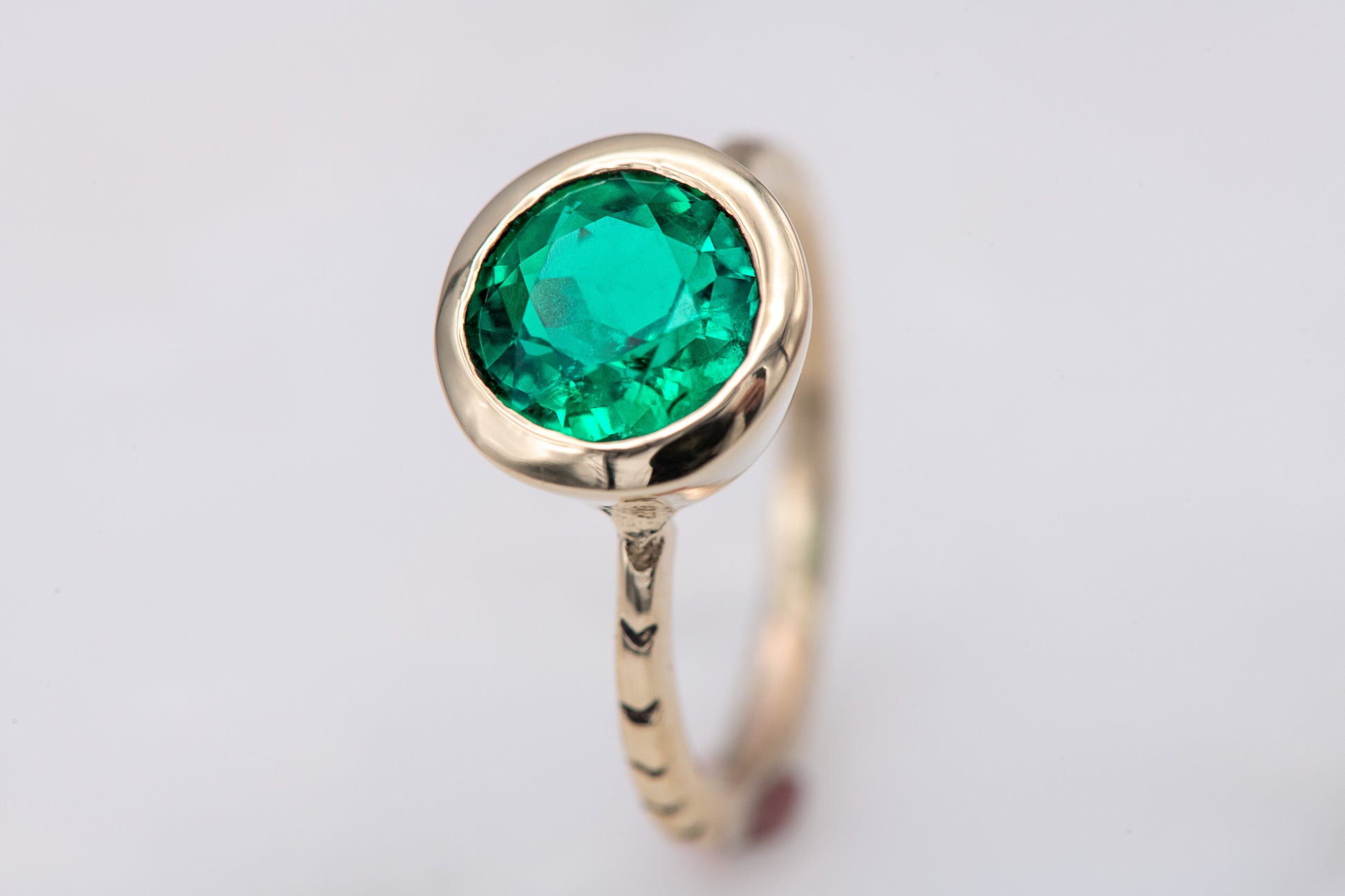 A handmade Emerald and Yellow Gold Engagement Ring by Cassin Jewelry.