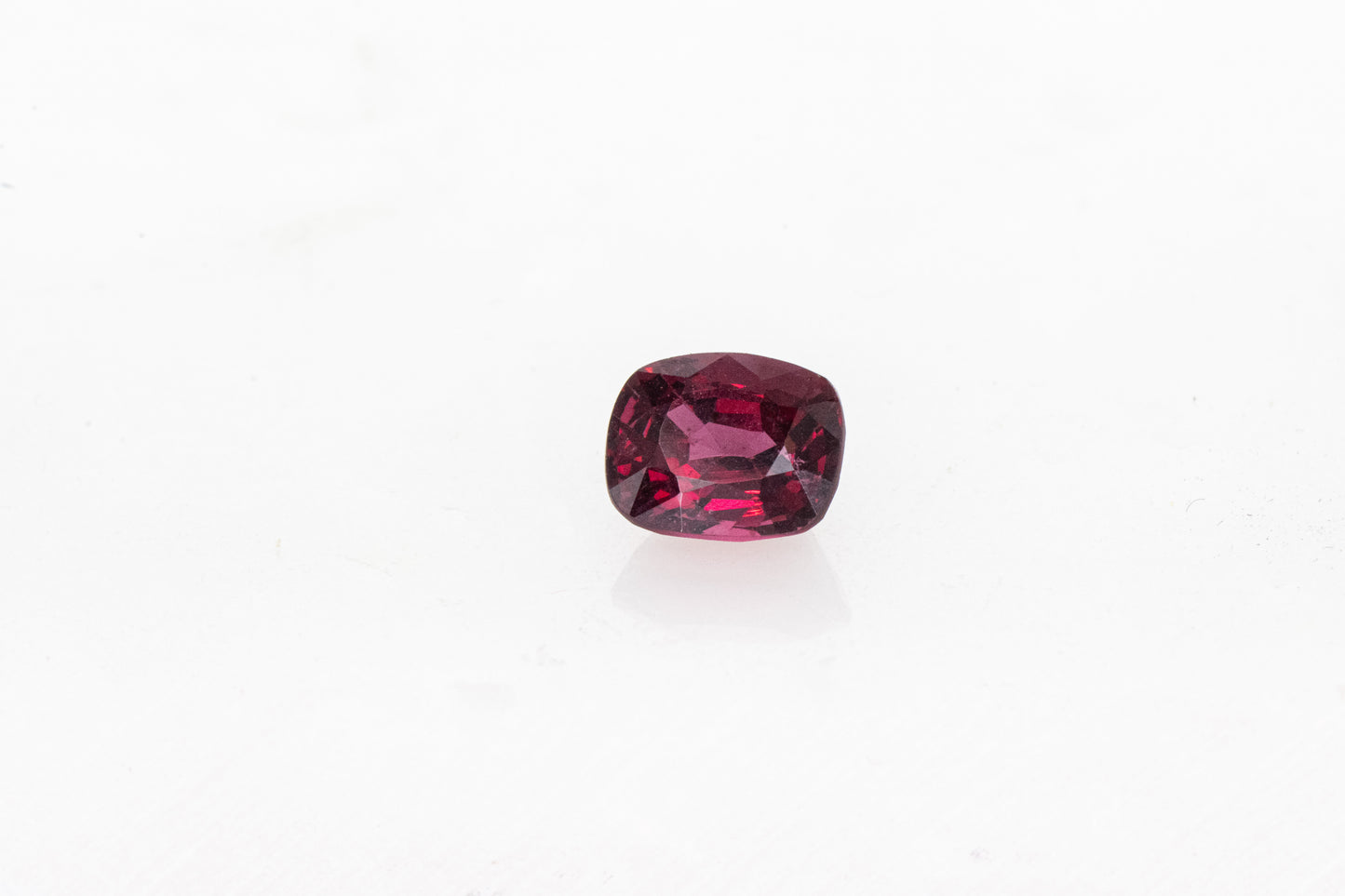 A Red Spinel Cushion Cut 8x6MM gemstone on a white background by Cassin Jewelry.