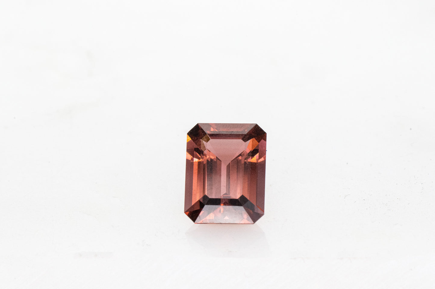A rectangular shaped Pink Tourmaline Emerald Cut 10.5x7.5mm on a white surface, handmade by Cassin Jewelry.