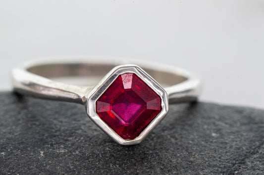 A handmade Asscher Cut Ruby Ring in Sterling Silver with a ruby stone on top of a rock from Cassin Jewelry.