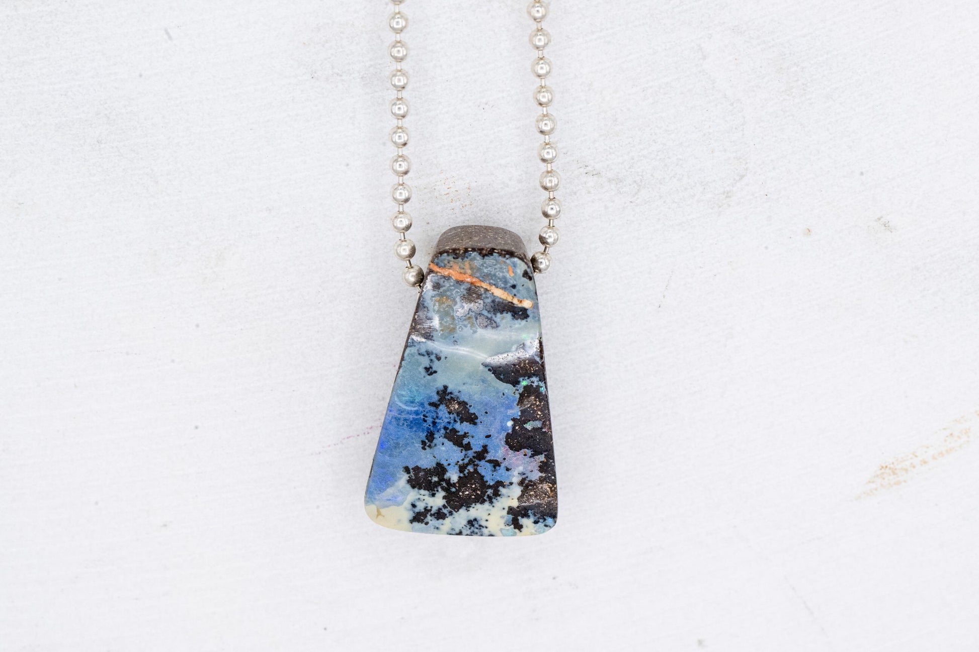 A unique Australian Opal Necklace with handmade jewelry and a blue stone.