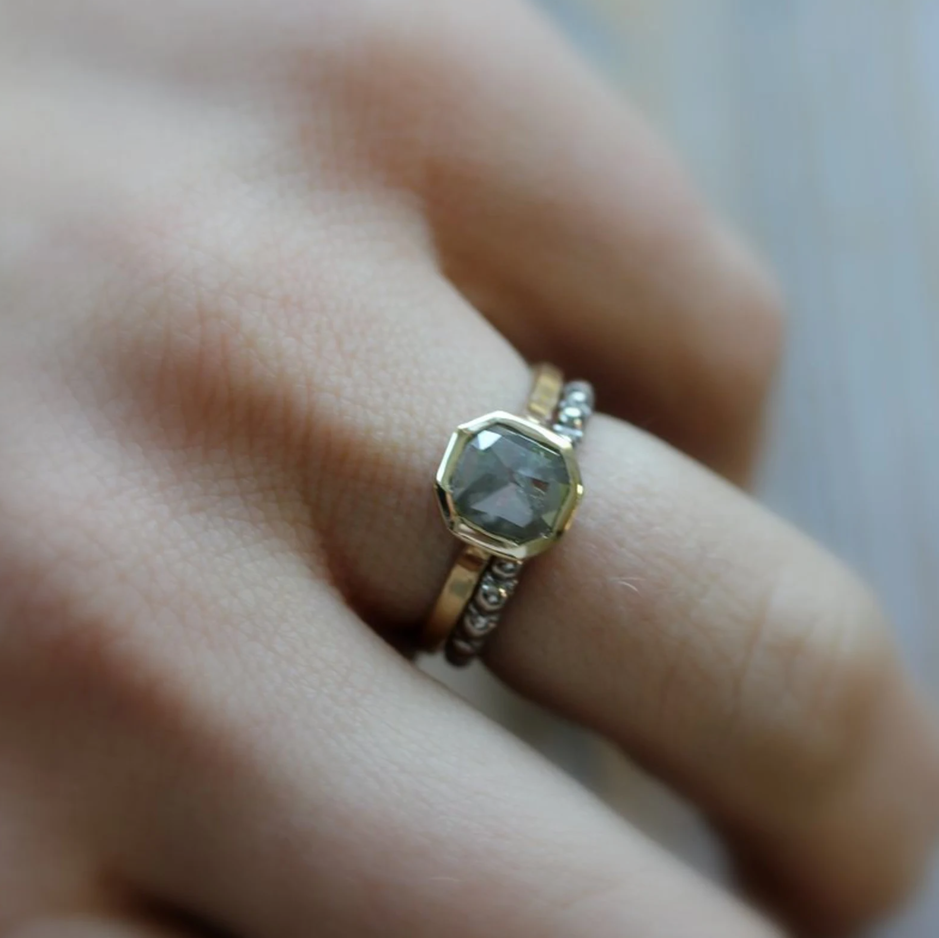 A woman's hand holding a handmade Cassin Jewelry Rose Cut Gray Diamond Ring in 14k Yellow Gold.