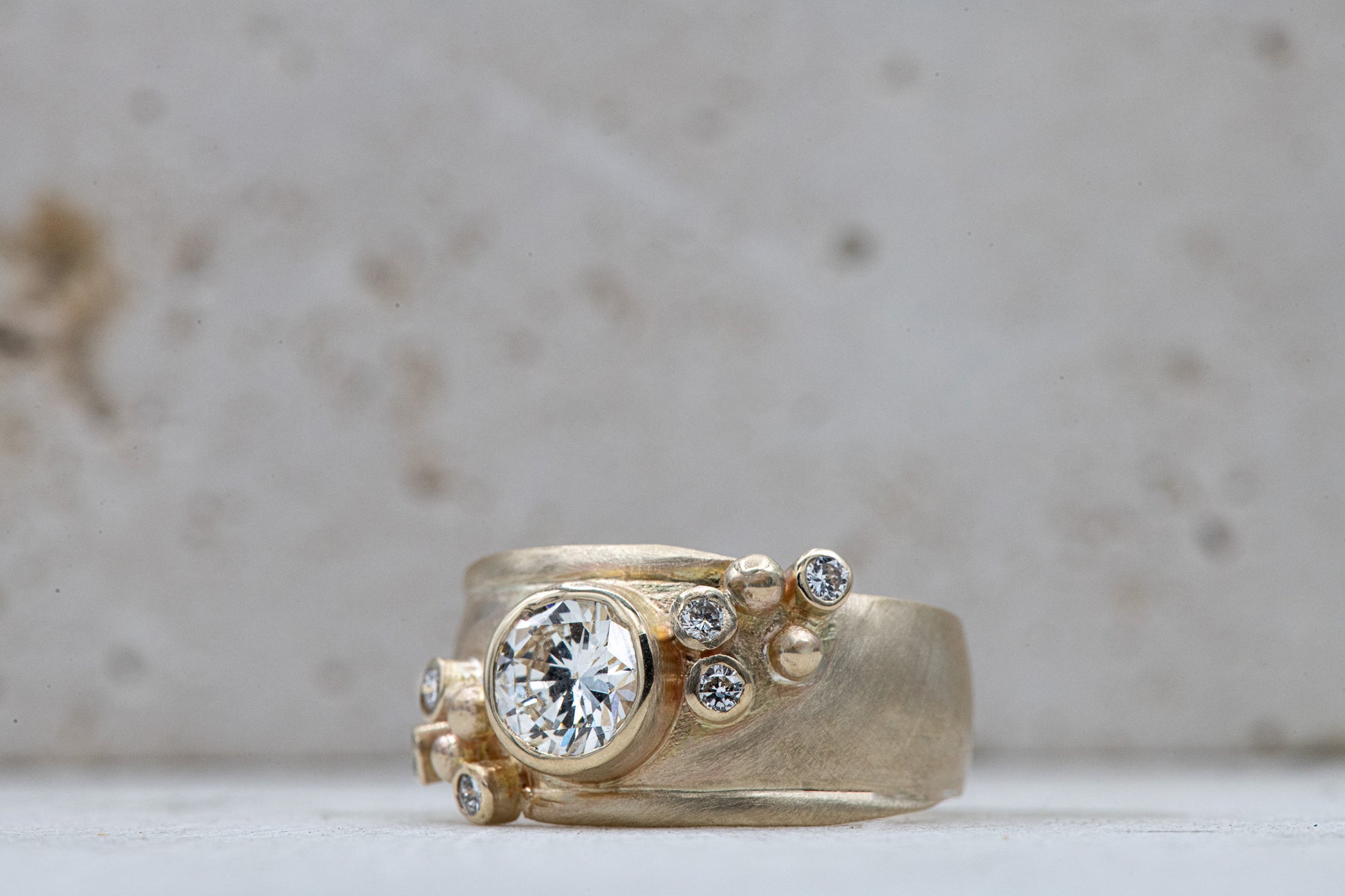 A handmade Wide Forever One Moissanite Gold Ring with a diamond in the center.
