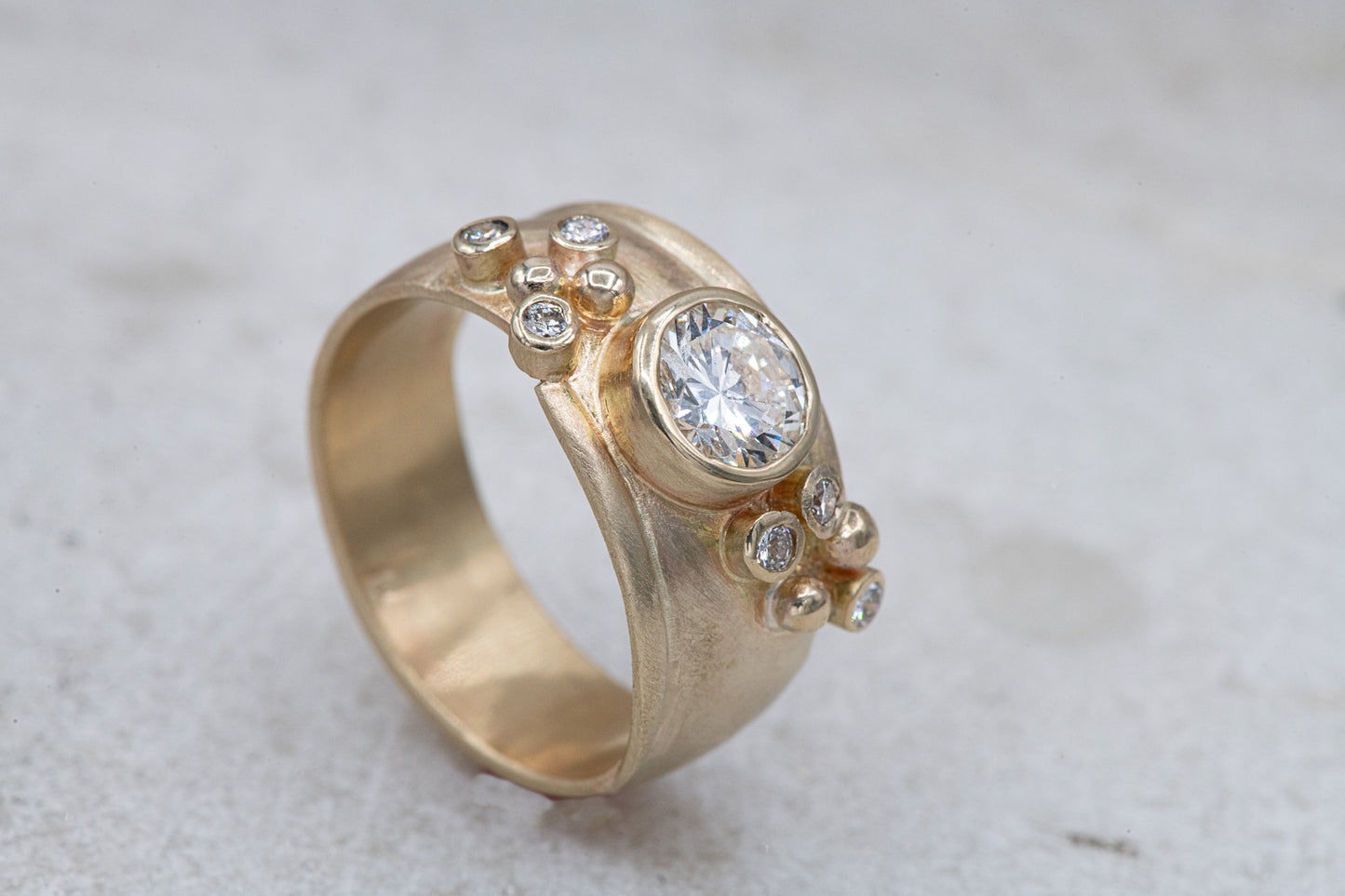 A Wide Forever One Moissanite Gold Ring with a diamond in the center, handcrafted by Cassin Jewelry.