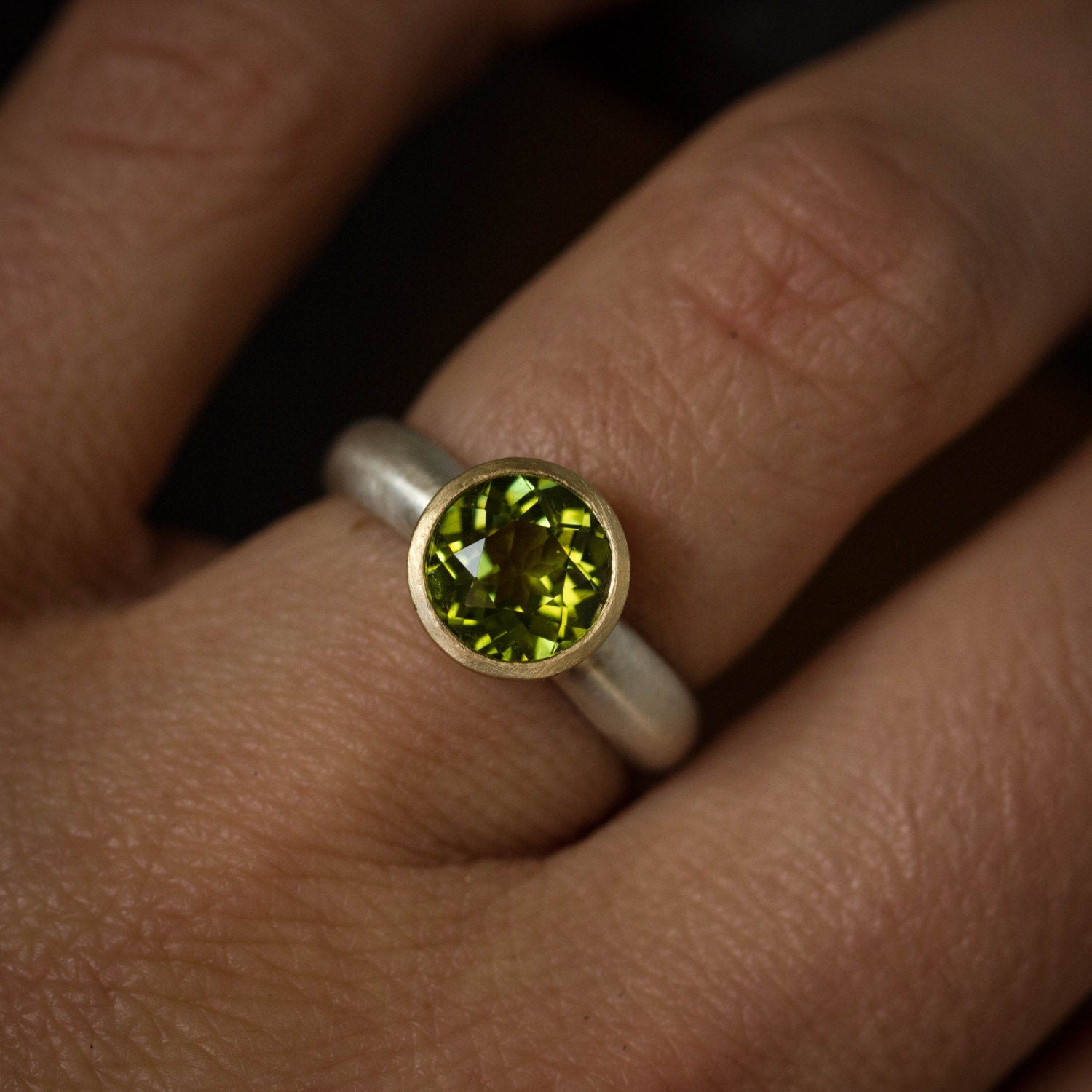 A woman's hand holding a handmade Peridot Mixed Metal Gemstone Ring from Cassin Jewelry.