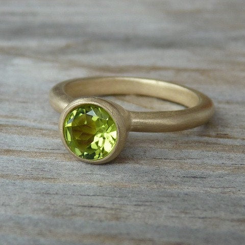 Handmade jewelry featuring a blue iolite and yellow gold ring with a peridot stone.