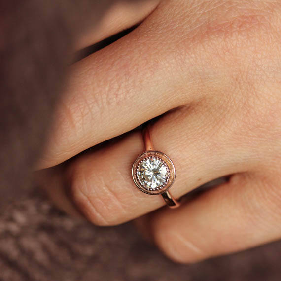 A woman's hand adorned with a Round Forever One Moissanite Engagement Ring, crafted by Cassin Jewelry.