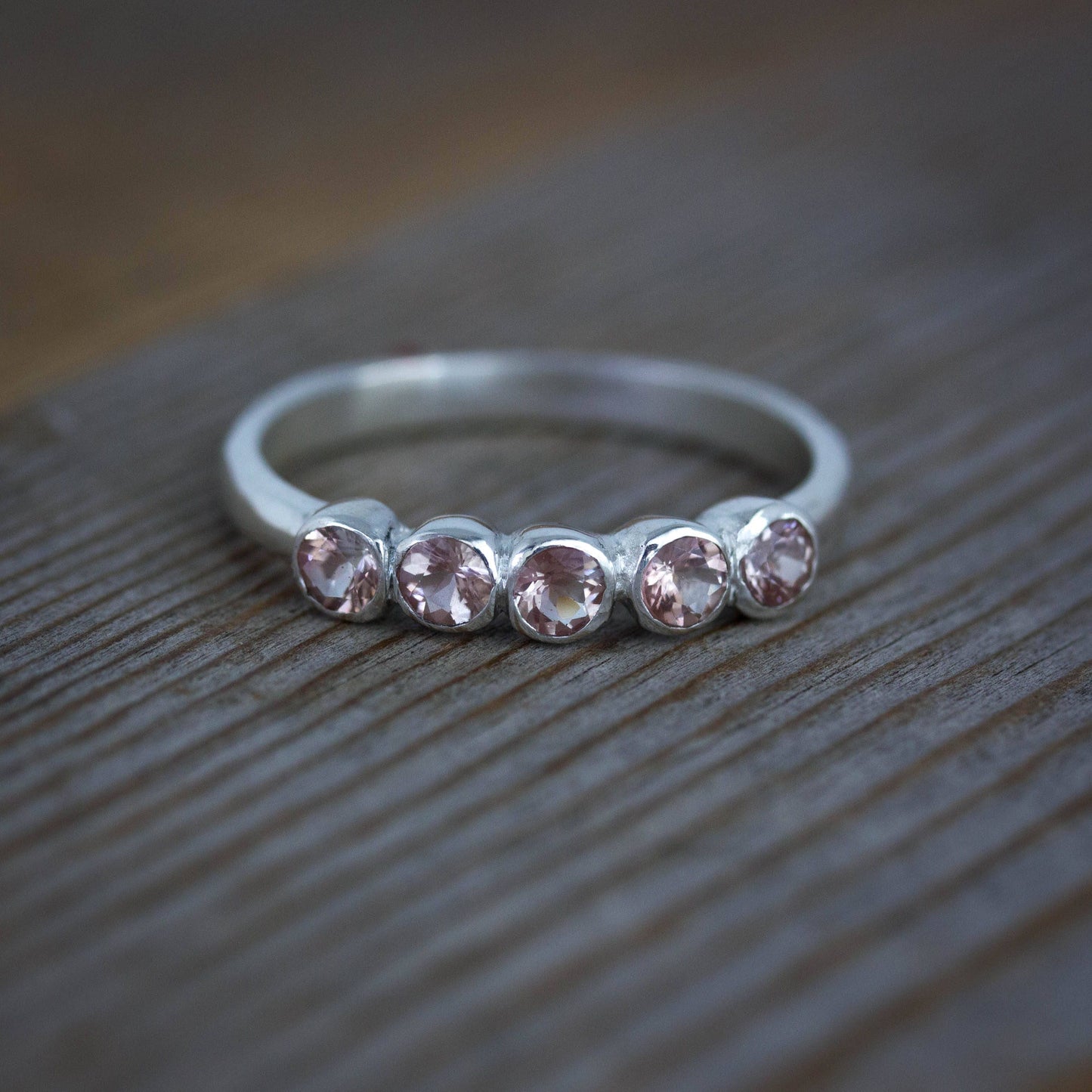 A Cassin Jewelry handmade ring featuring a Silver Oregon Sunstone Band with pink topaz stones.