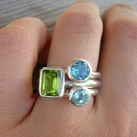 A woman wearing handmade Peridot and Swiss Blue Topaz Gemstones Stacking Rings in Sterling Silver by Cassin Jewelry.