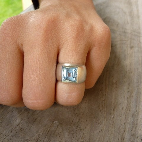 A woman wearing a handmade Sterling Silver Square Princess Cut Ring with a blue topaz stone.