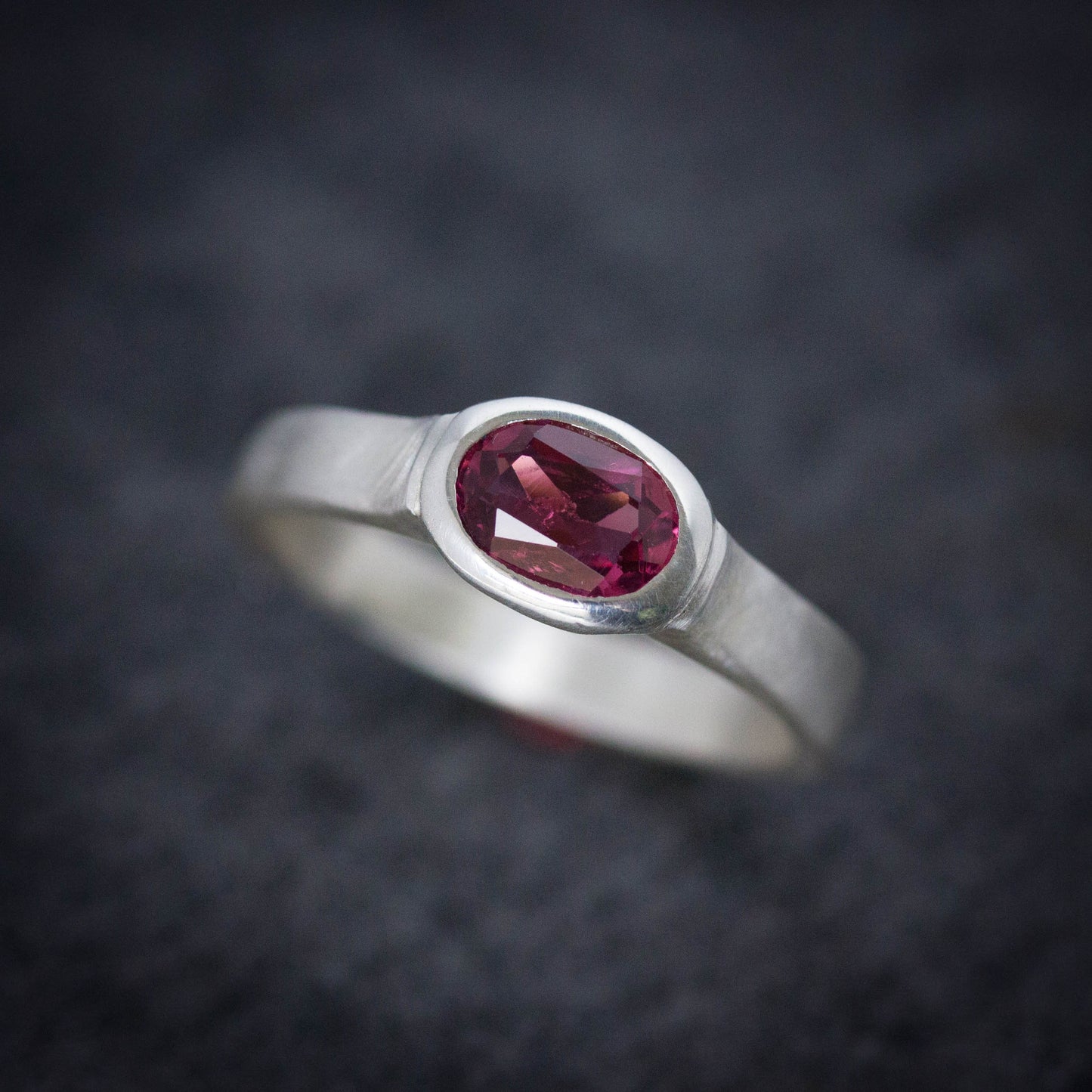 A Handmade Pink Tourmaline Wide Band Ring, Brushed Silver With Low Profile, Size 7 Oval Gemstone Solitaire and October Birthstone with a ruby stone by Cassin Jewelry.