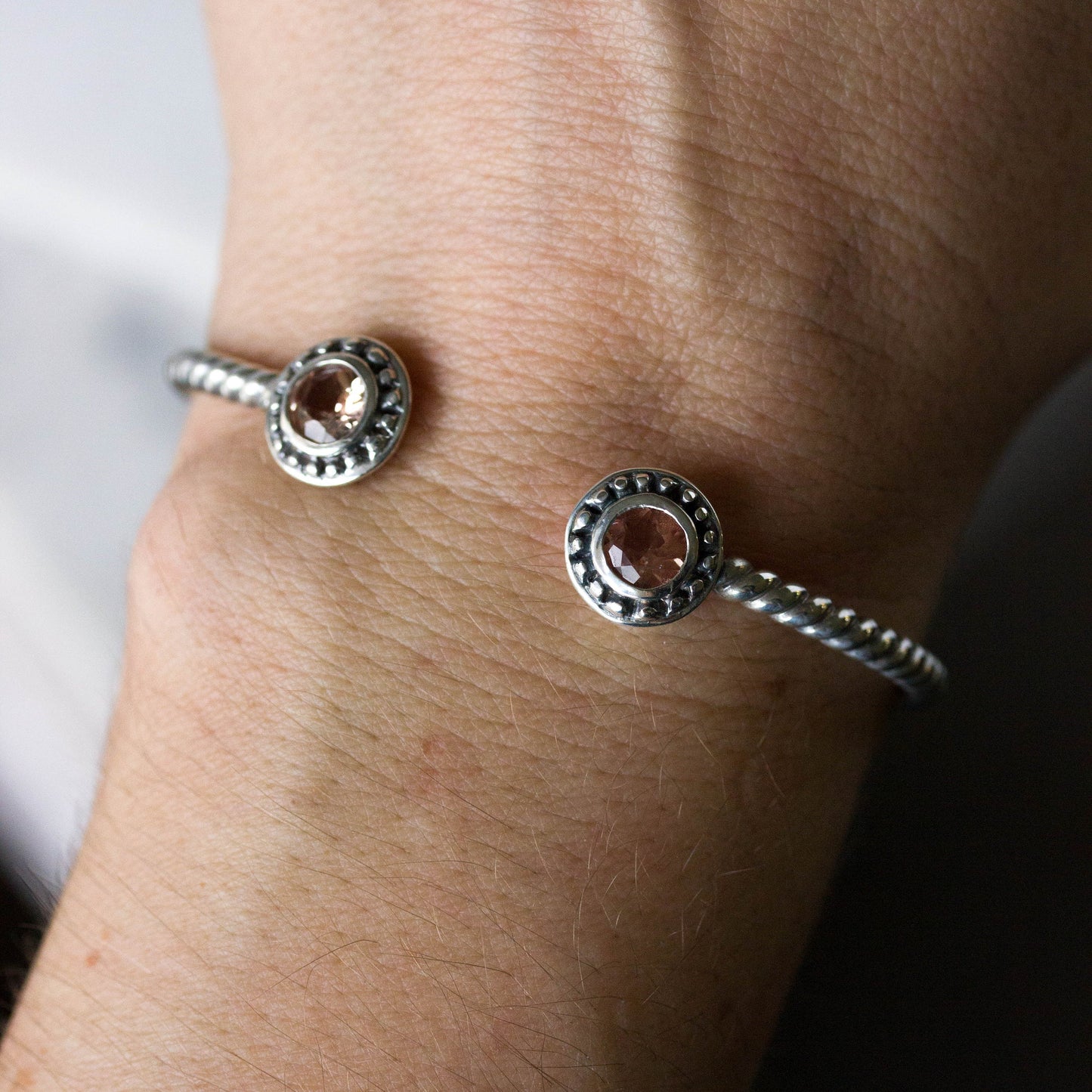 A woman's wrist adorned with a handmade Peach Oregon Sunstone Bracelet by Cassin Jewelry.