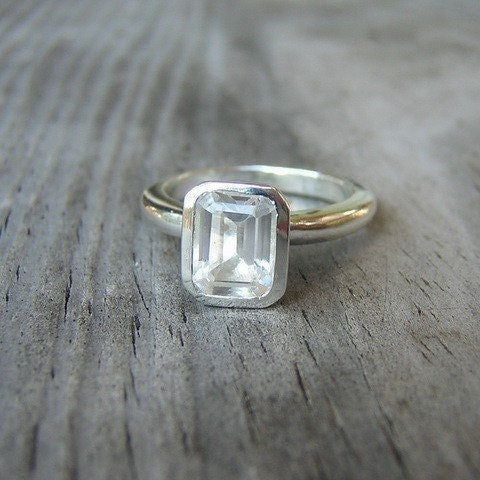 Handmade Emerald White Topaz Gemstone ring in Silver on a wooden surface.