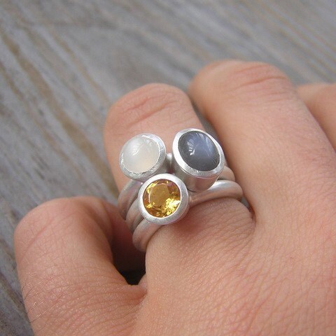 A person wearing a handmade Moonstone Stacking Ring Set with a yellow stone.