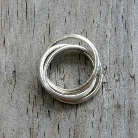 A stack of handmade Silver Spinner Rings with Celtic Wedding Rings on a wooden surface.