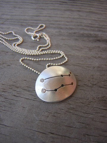 A Handmade Silver Gemini Constellation Necklace with a zodiac sign on it.