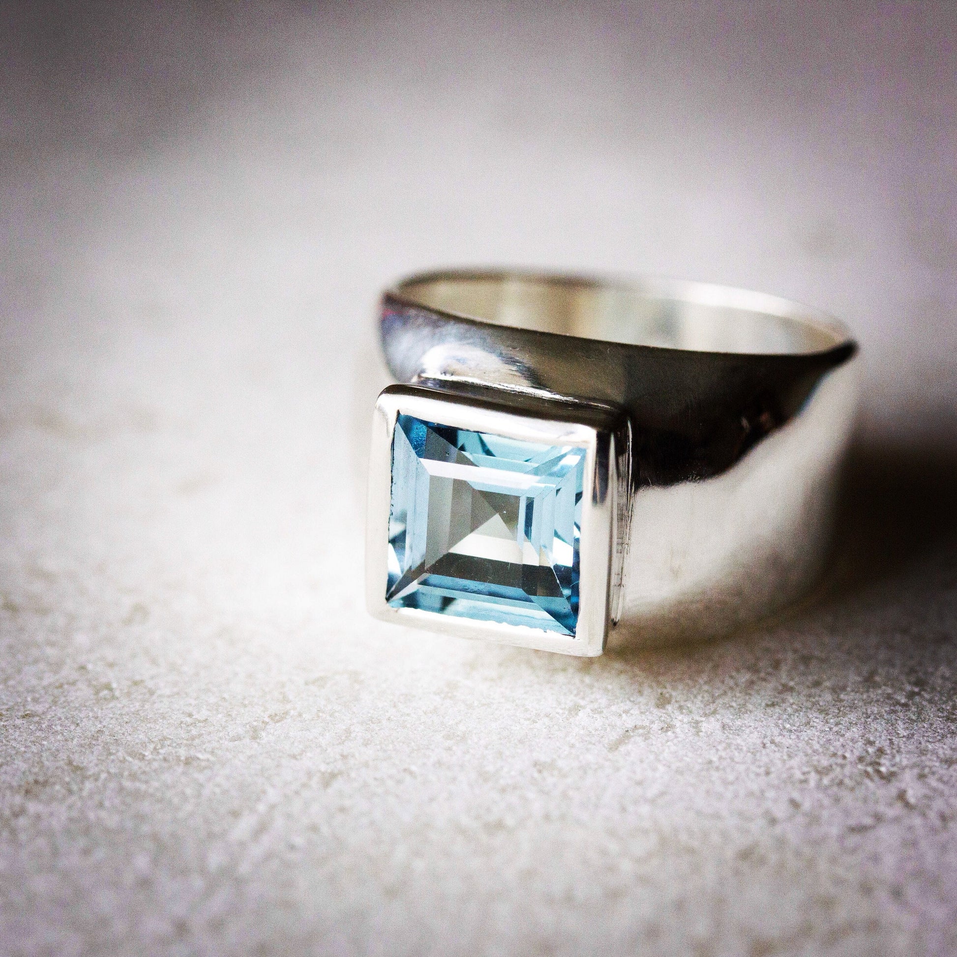 A handmade Sterling Silver Princess Cut Ring with a blue topaz stone.