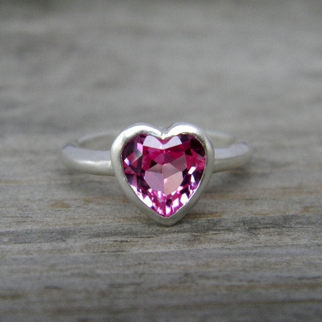 A Pink Heart Shaped Topaz ring on a wooden surface, created by Cassin Jewelry.