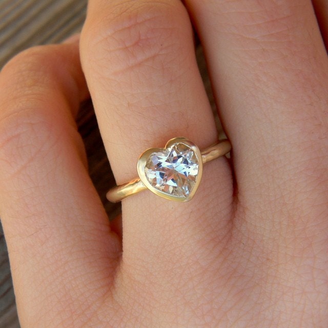 A woman's hand with a Heart Shaped White Topaz Ring in Yellow Gold - handmade jewelry.