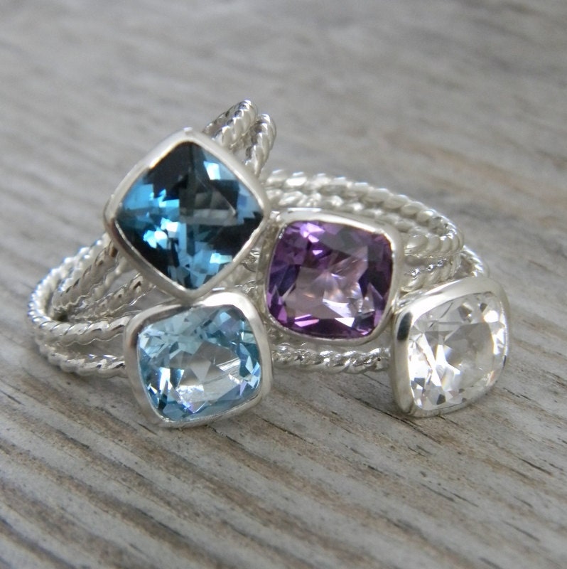 Handmade jewelry featuring sterling silver rings with blue topaz, purple amethyst cushion cut and emerald.