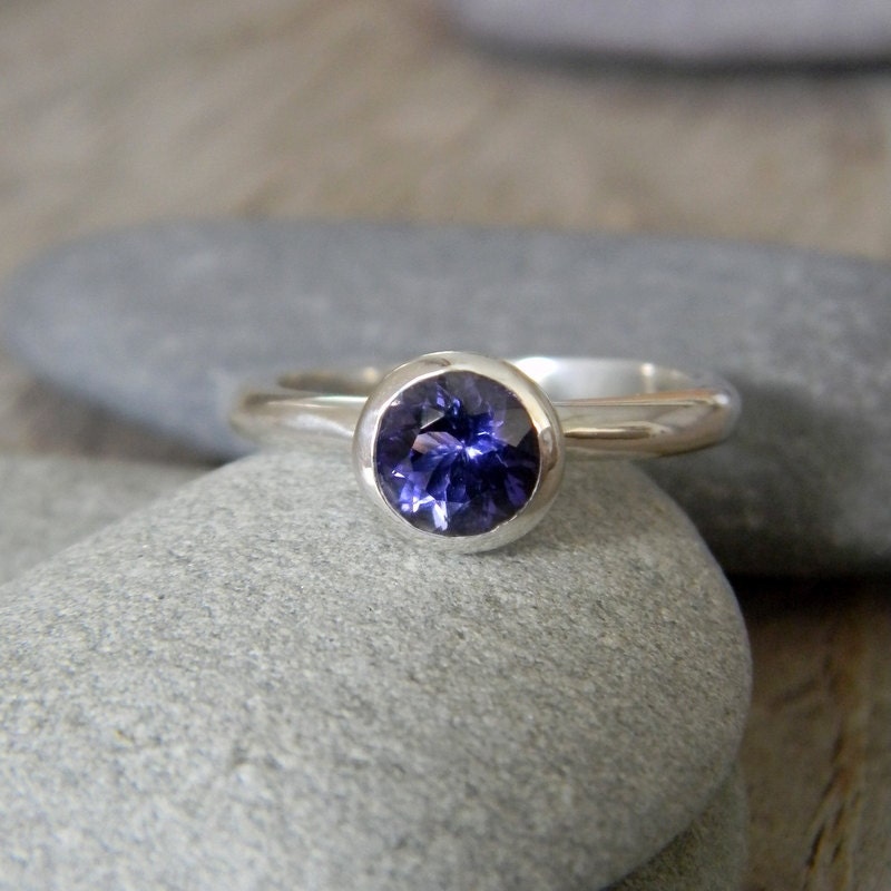 Handmade jewelry featuring an iolite stone atop a rock.