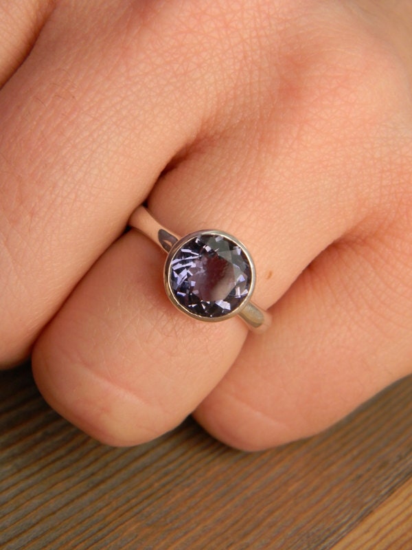 A woman's hand is holding an Iolite Silver Gemstone Ring, a handmade Cassin jewelry.