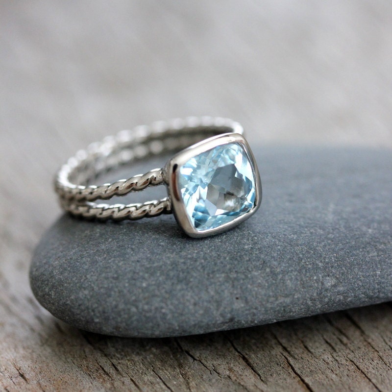 A handmade Sky Blue Topaz Ring with a blue topaz stone on top of a rock.