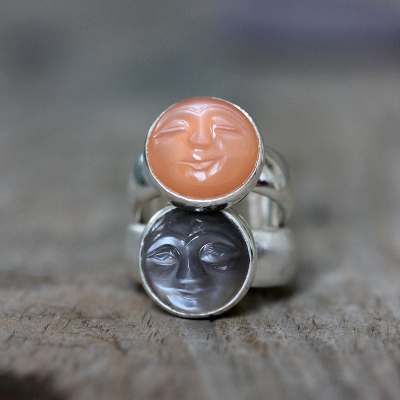 A handmade Moonstone Face Ring by Cassin Jewelry with two faces on it.
