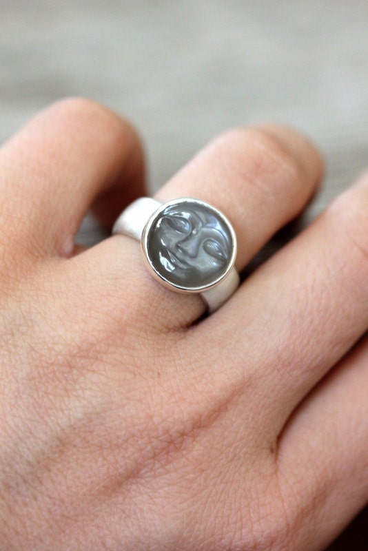 A woman's hand is holding a handcrafted Moonstone Face Ring.