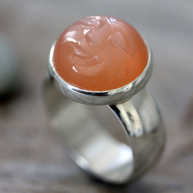 A handmade Peach Moonstone Ring with an orange stone on it by Cassin Jewelry.