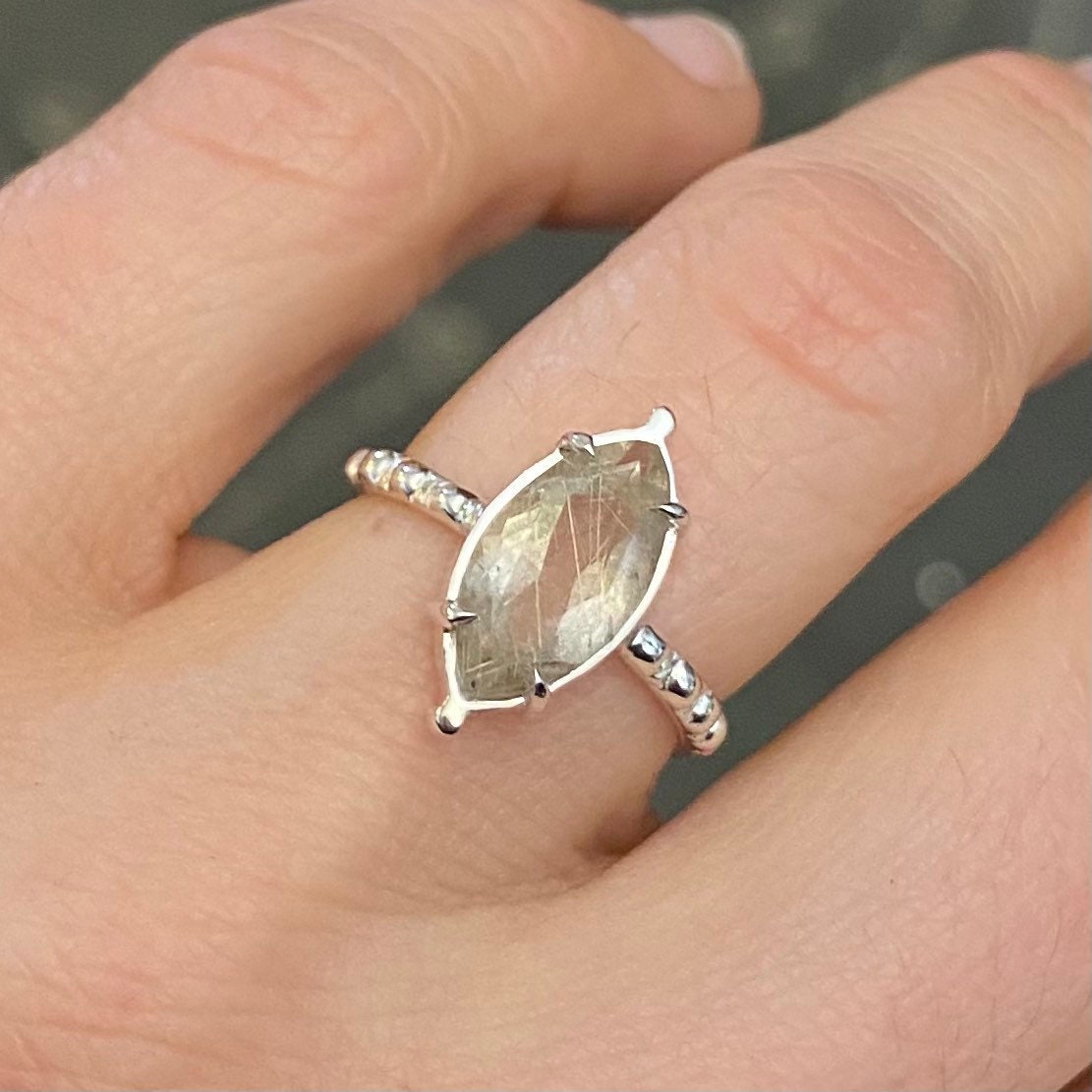 A woman wearing a handmade Rutile Quartz and Vintage Sterling Silver Milgrain Band Ring with a Diamond Shape Stone, crafted by Cassin Jewelry.