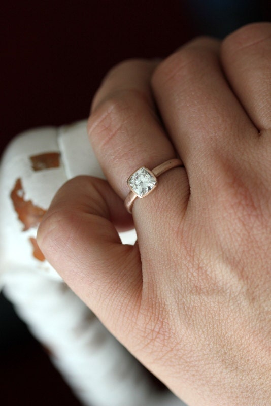 A woman's hand holding a handmade Cushion Cut Rose Gold Engagement Ring.