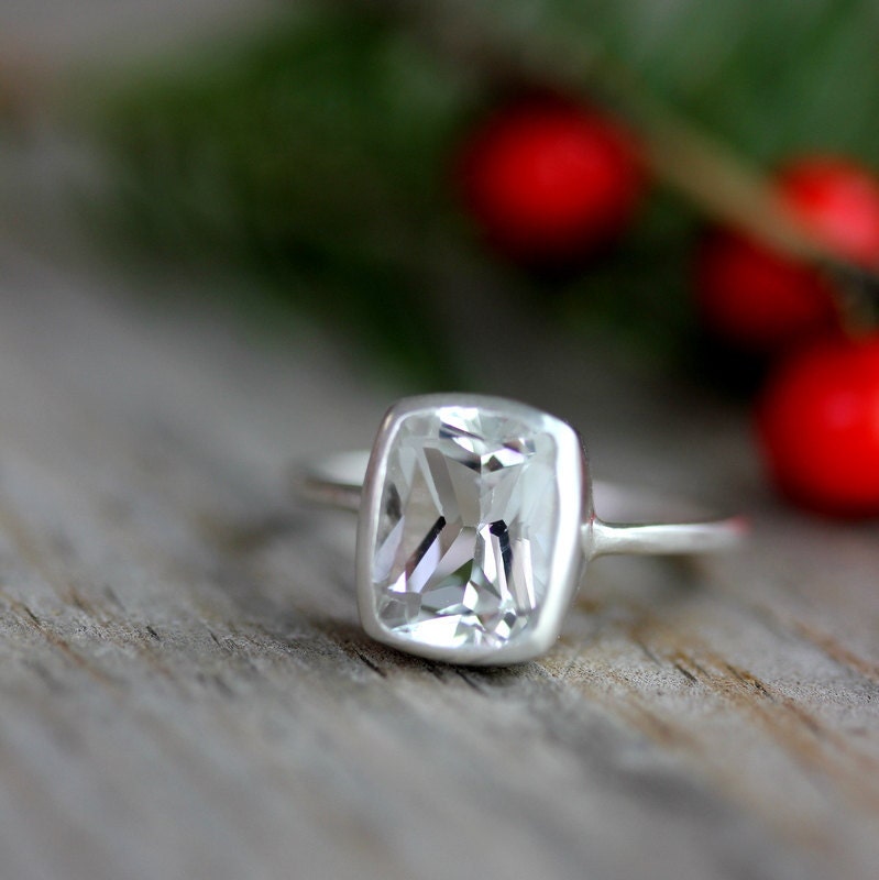 A Handmade Cushion White Topaz Ring on a wooden table.