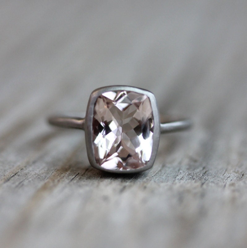 A handmade Morganite Ring on a wooden surface.
