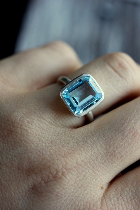 Handmade jewelry - a woman's hand holding a Sky Blue Topaz Emerald Cut Ring in Recycled Silver by Cassin Jewelry.
