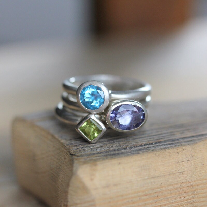 Handmade jewelry featuring a stack of Nesting Rings In Oval Iolite, Princess Cut Peridot Ring and Swiss Blue Topaz adorned with peridots and amethyst.