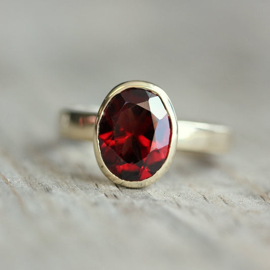 A handmade Red Garnet Ring in 14k Yellow Gold Bezel Setting with a red garnet stone by Cassin Jewelry.
