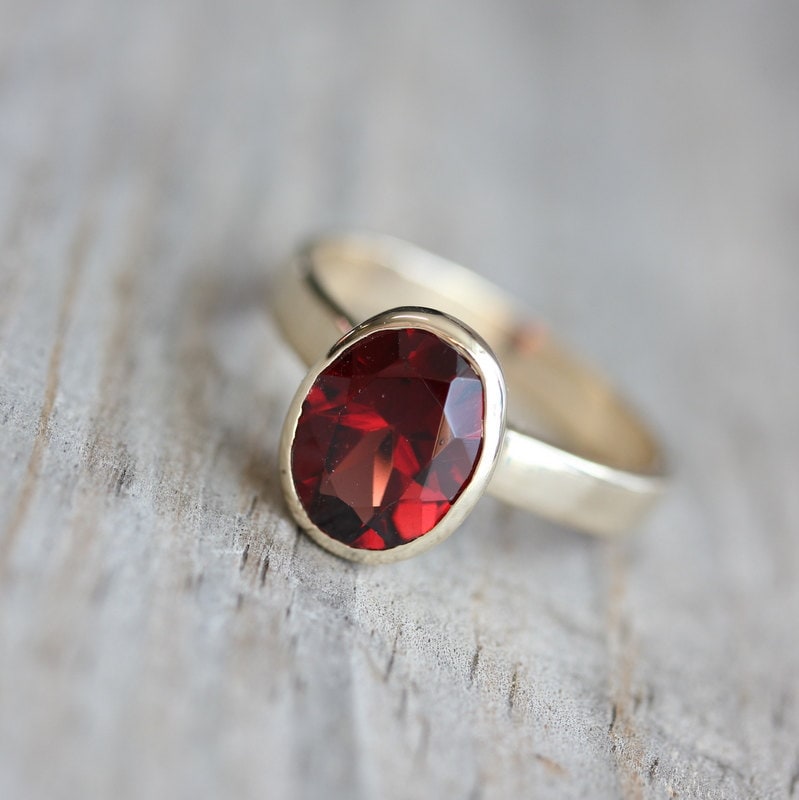 A Handmade Oval Red Garnet Ring in 14k Yellow Gold Bezel Setting with a red stone.