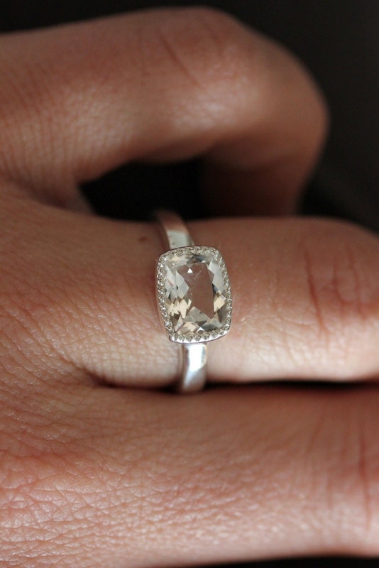 A woman's hand with a Vintage Inspired White Topaz Cushion Cut Ring in Sterling Silver, handmade jewelry.